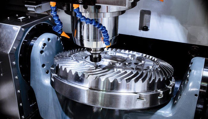 A modern CNC milling machine makes a large cogwheel.
